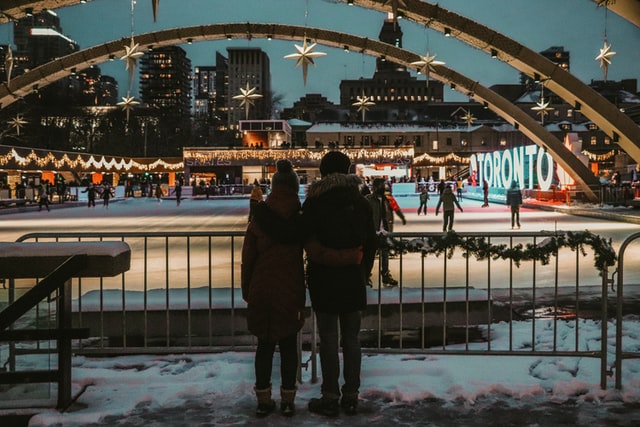 2 people standing by a bridge during the winter holiday looking out at a city!