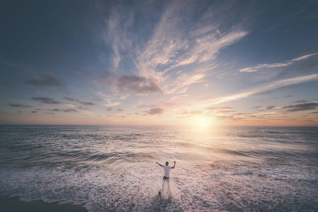 Sunset with man on the shore watching the tide.