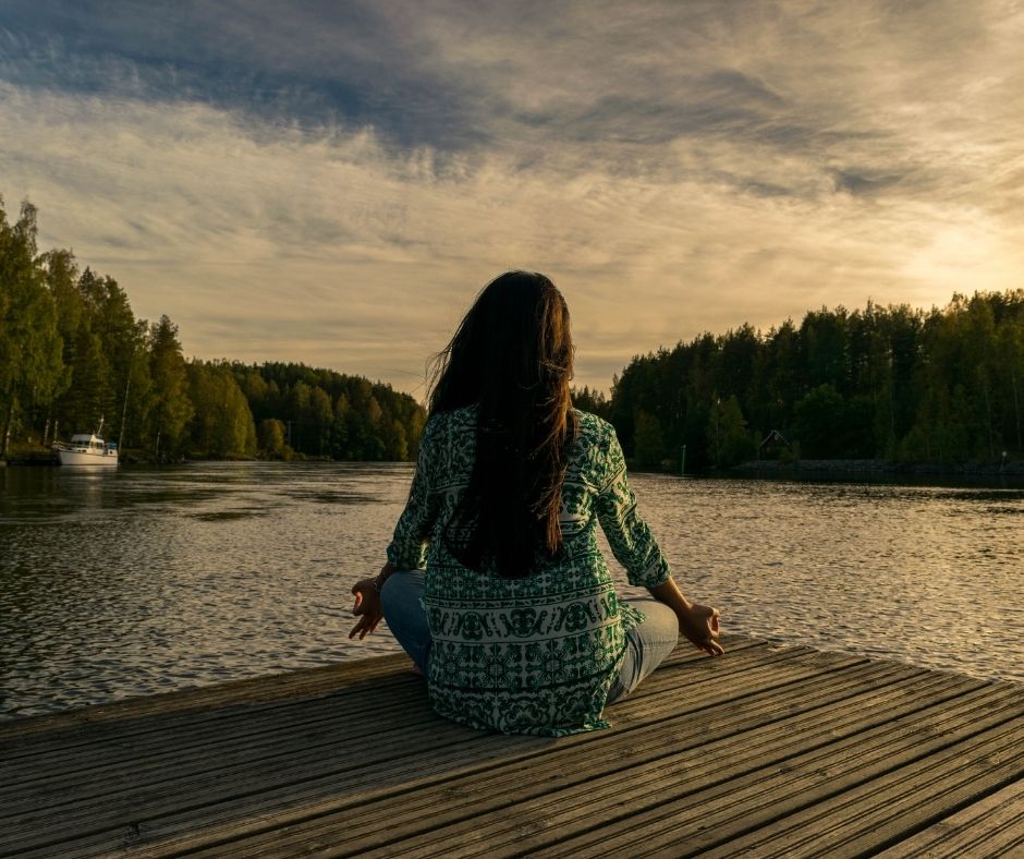 Woman meditating on lake