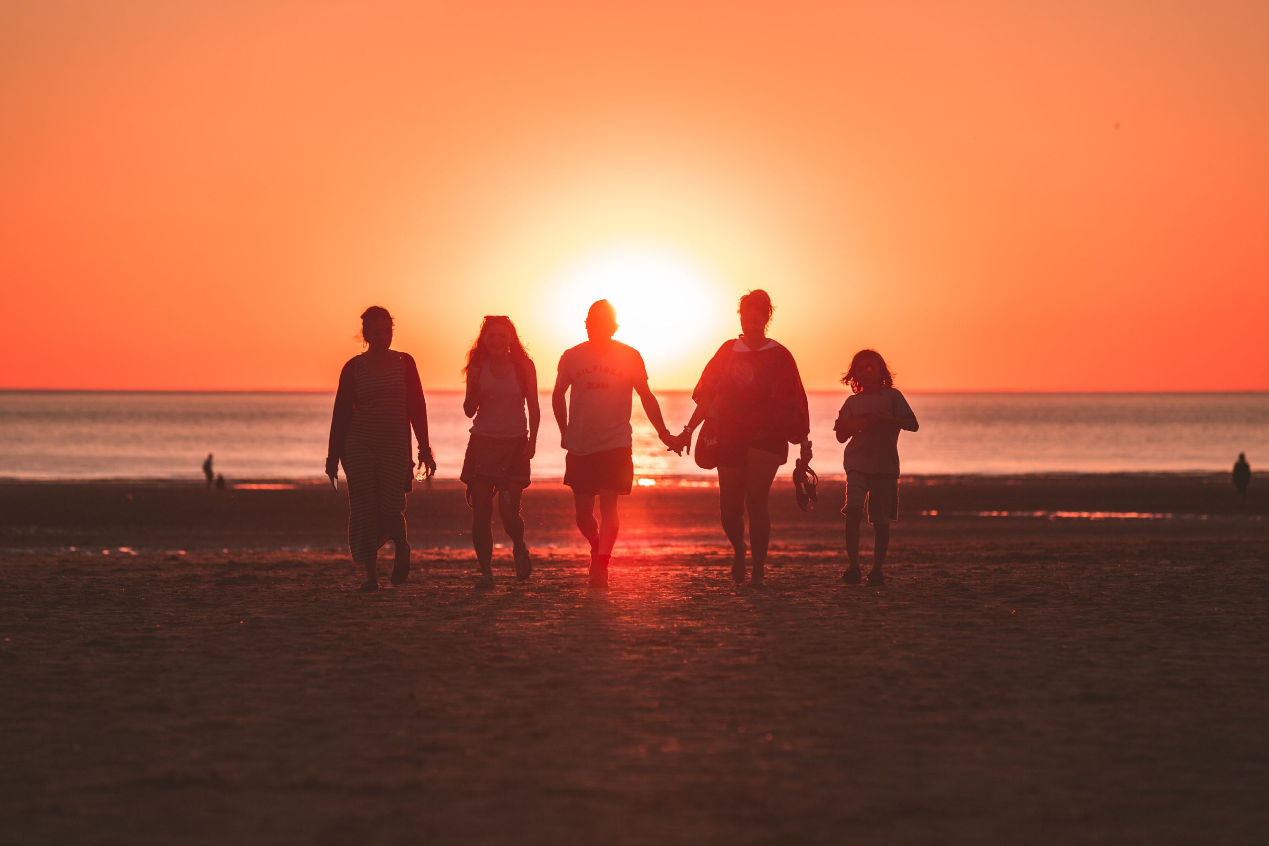 Friends walking towards the beach at sunset.